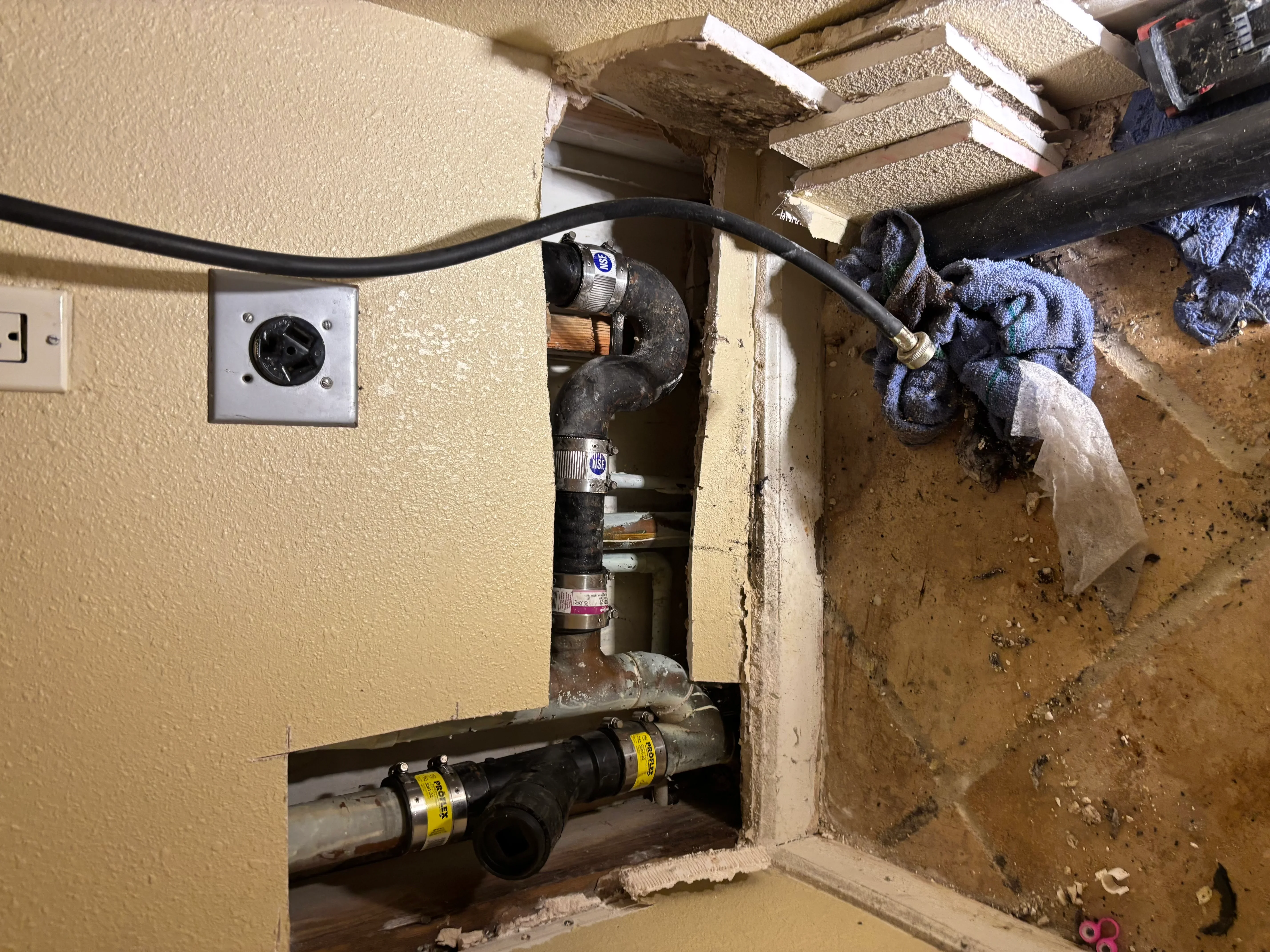 Basement plumbing with PVC drains, black supply lines, and outlet timer control installed