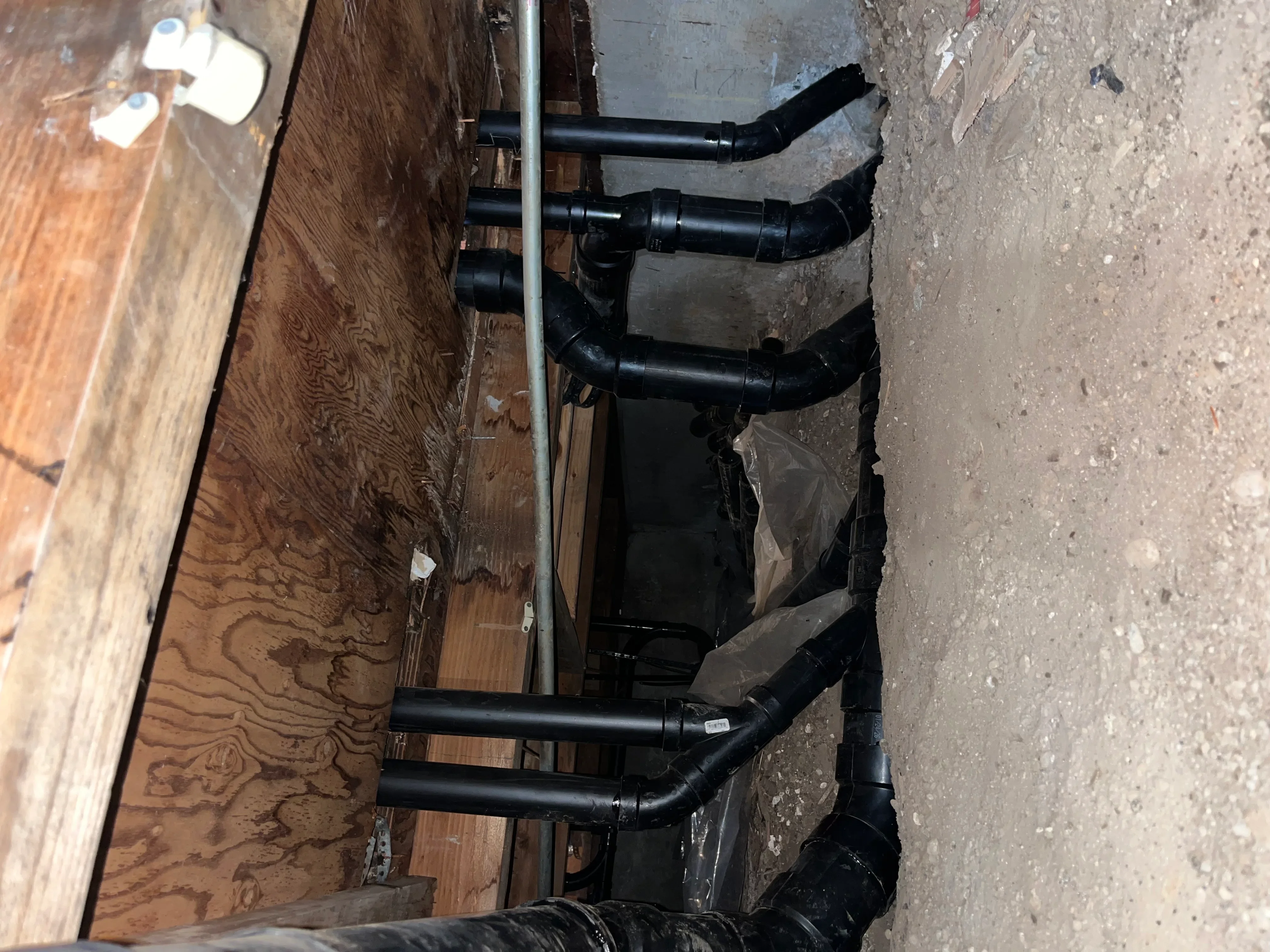 Black PEX water lines with elbows and fittings installed along foundation