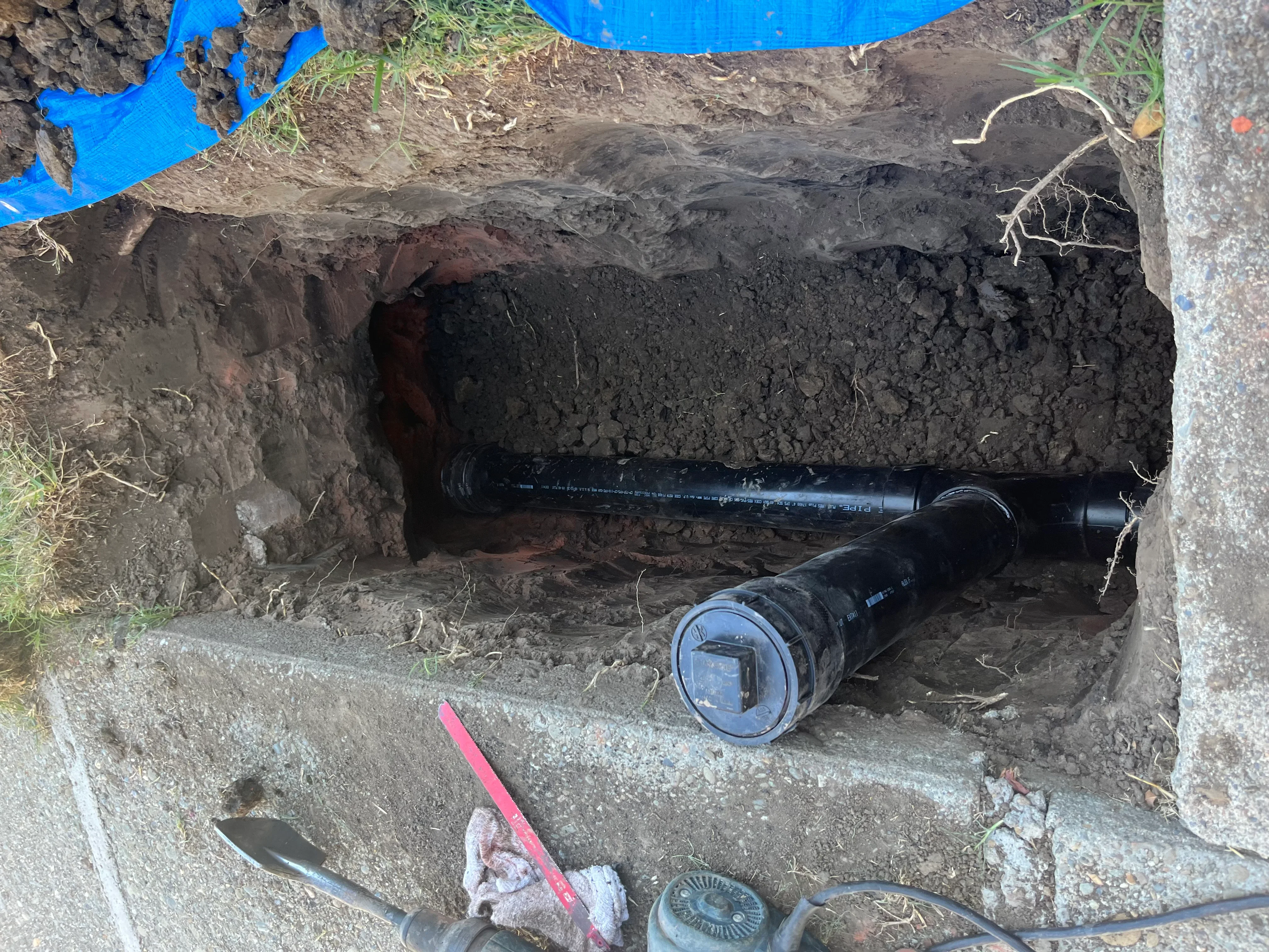 Black PVC sewer pipe installed in underground trench with soil excavation