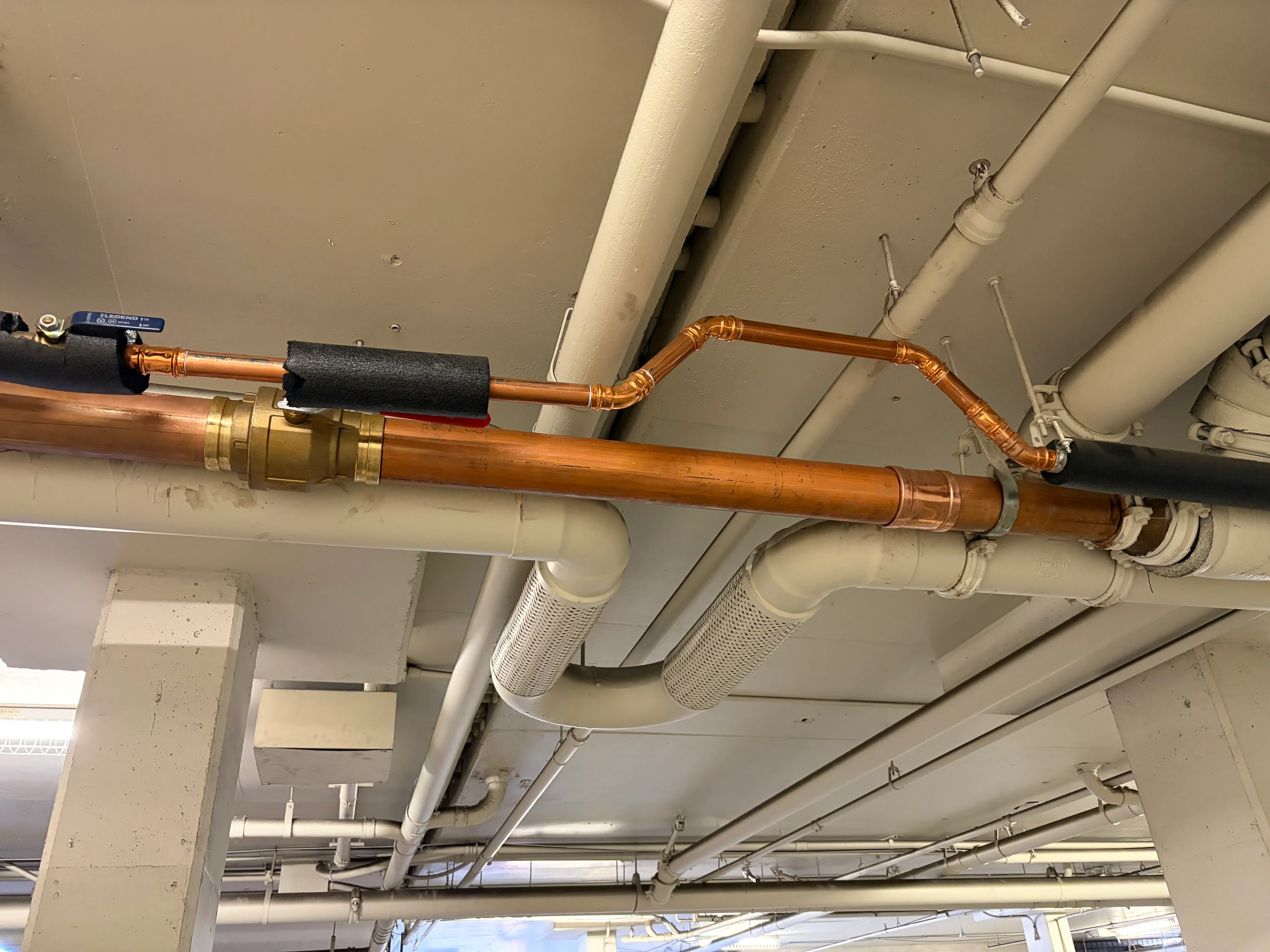 Copper radiant heating pipes with brass valves and foam insulation installed on ceiling