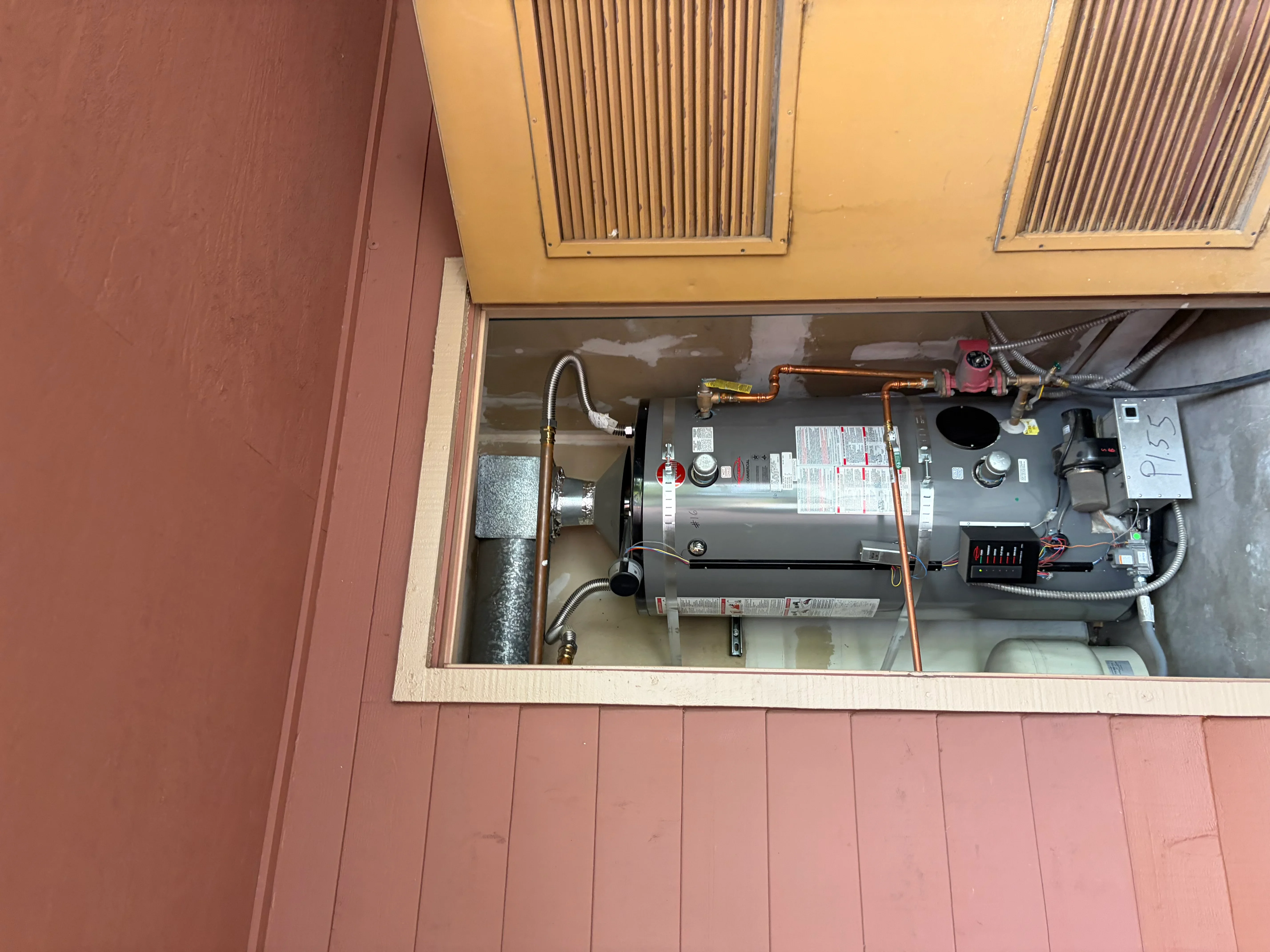 Tankless water heater with copper piping, controls, and louvered ventilation enclosure