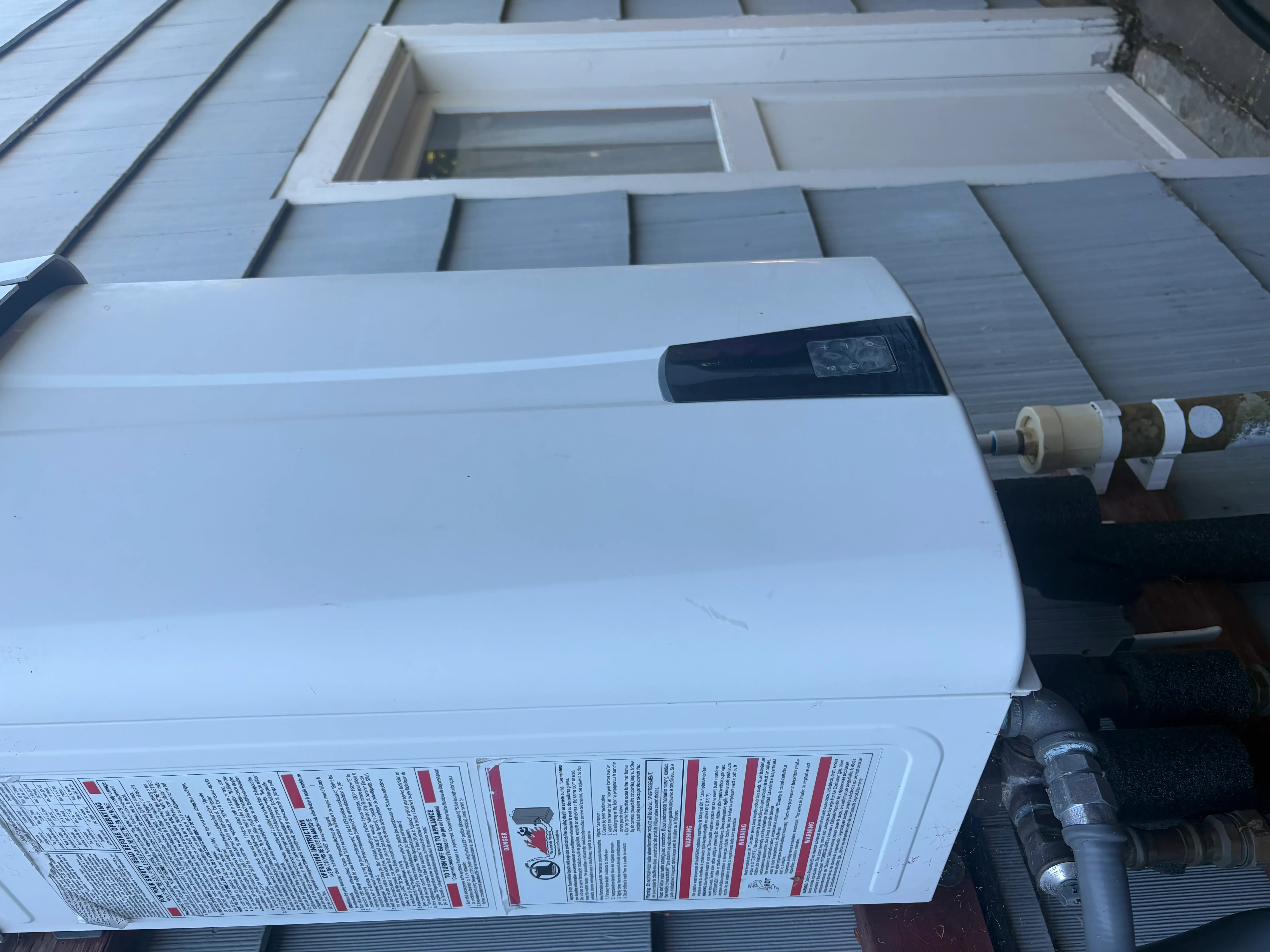 Tankless water heater with copper fittings installed on metal roof with supply lines